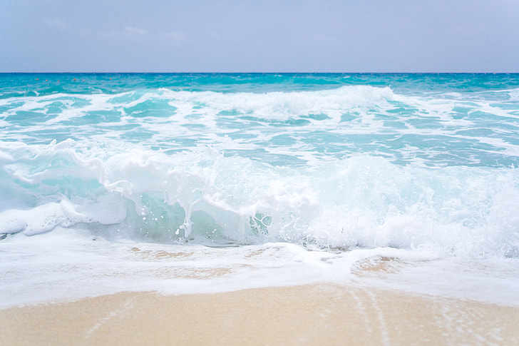 Two Young Girls Are Playing In The Ocean Waves On A Sandy Beach